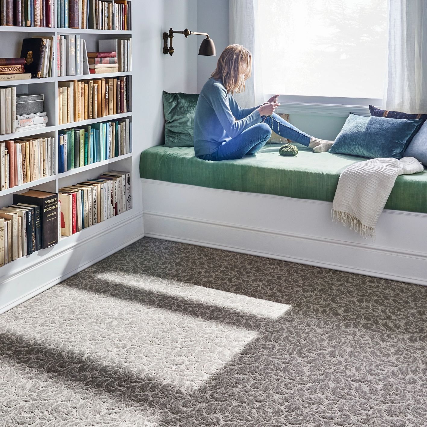 Person reading in window in bedroom with brown patterned carpet from Carpet City & Flooring Center in the Fairfield, CT area